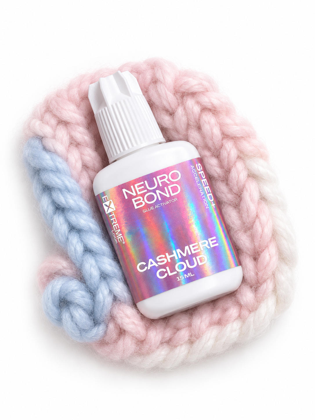 Acceleratore per colla Extreme Look "Cashmere Cloud" appoggiato su un morbido intreccio di lana dai toni pastello. Il preparatore chimico indispensabile per stabilizzare l'adesivo in condizioni di bassa umidità.