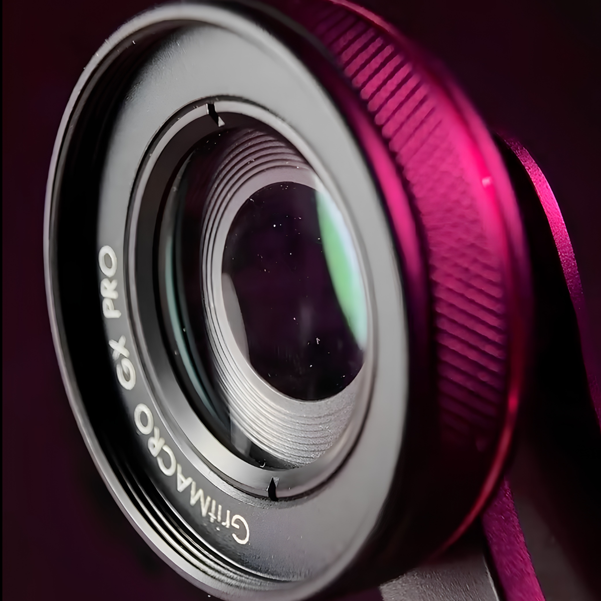 Dettaglio ravvicinato delle ottiche della lente macro GritMACRO GX PRO e dell'anello di filtro magenta-texture, contro uno sfondo scuro, evidenziando la qualità premium per la fotografia macro dettagliata.